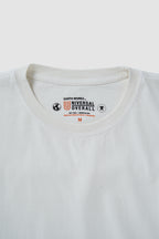 Close-up of a white t-shirt with a brand logo on the collar against a light gray background